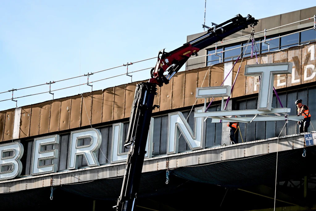 Arbeiter montieren den Schriftzug „Berlin-Tempelhof“ auf dem Dach des ehemaligen Flughafens Tempelhof nach einer einjährigen Sanierung wieder an.