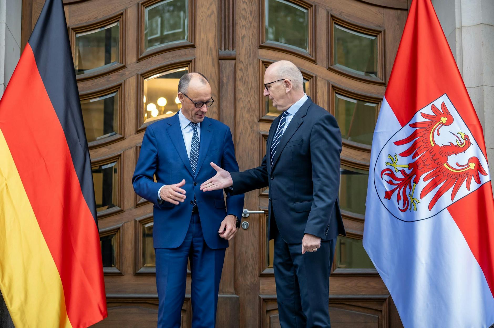 Bundeskanzler Friedrich Merz (lCDU) wird von Dietmar Woidke (SPD), Ministerpräsident von Brandenburg begrüßt.