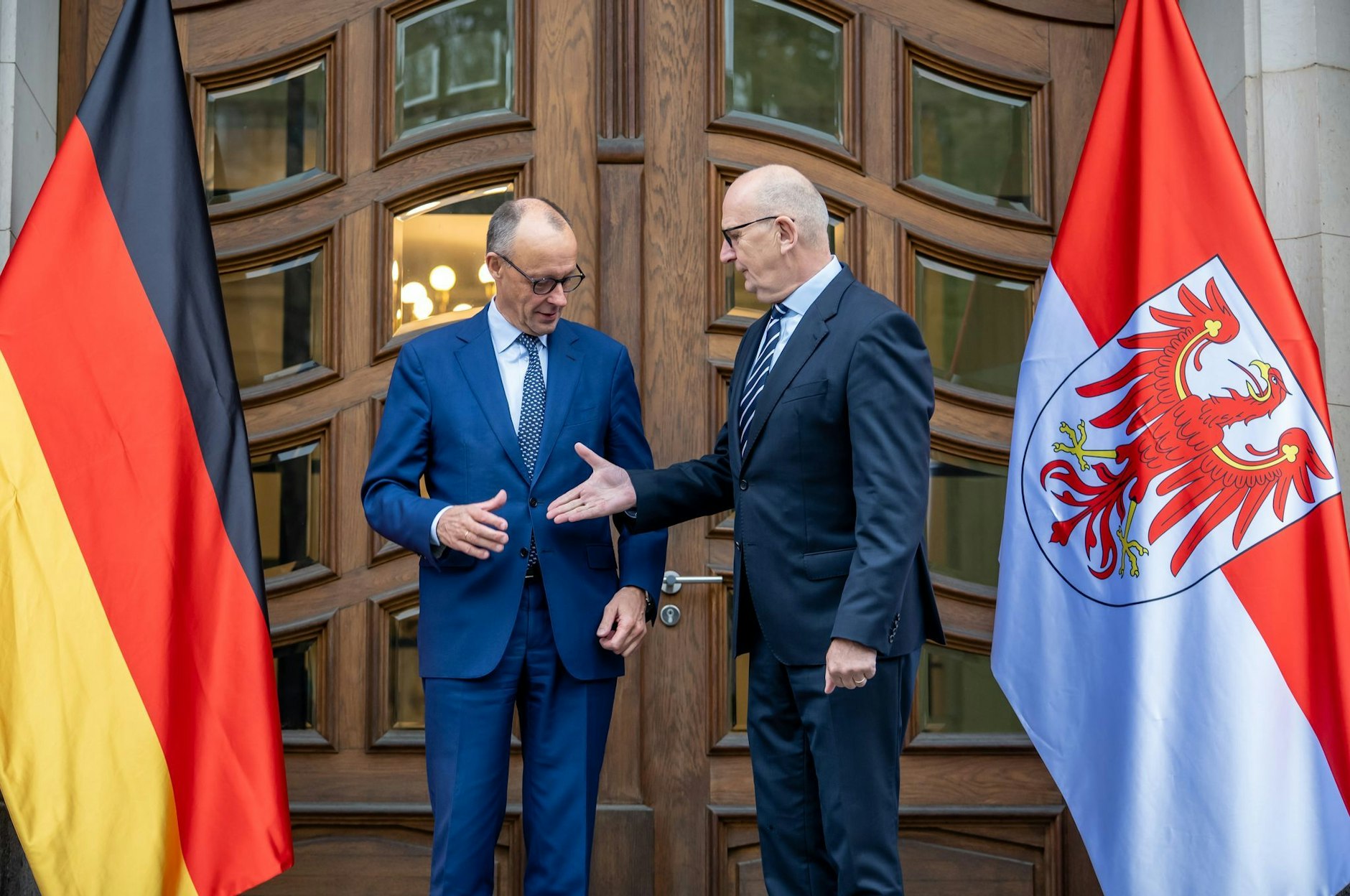 Bundeskanzler Friedrich Merz (lCDU) wird von Dietmar Woidke (SPD), Ministerpräsident von Brandenburg begrüßt.