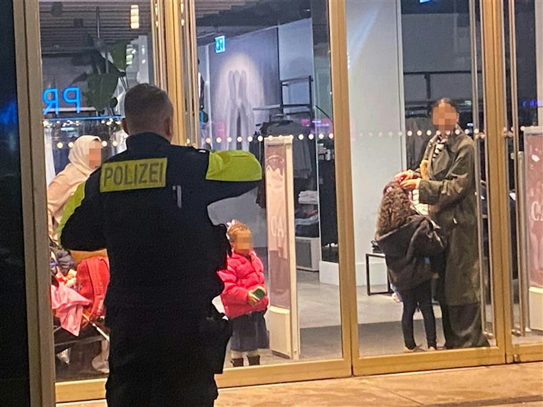 Ladenschluss verpasst: die eingesperrten Mütter mit ihren Kindern hinter der zugesperrten Eingangstür des Mode-Kaufhauses am Alexanderplatz.