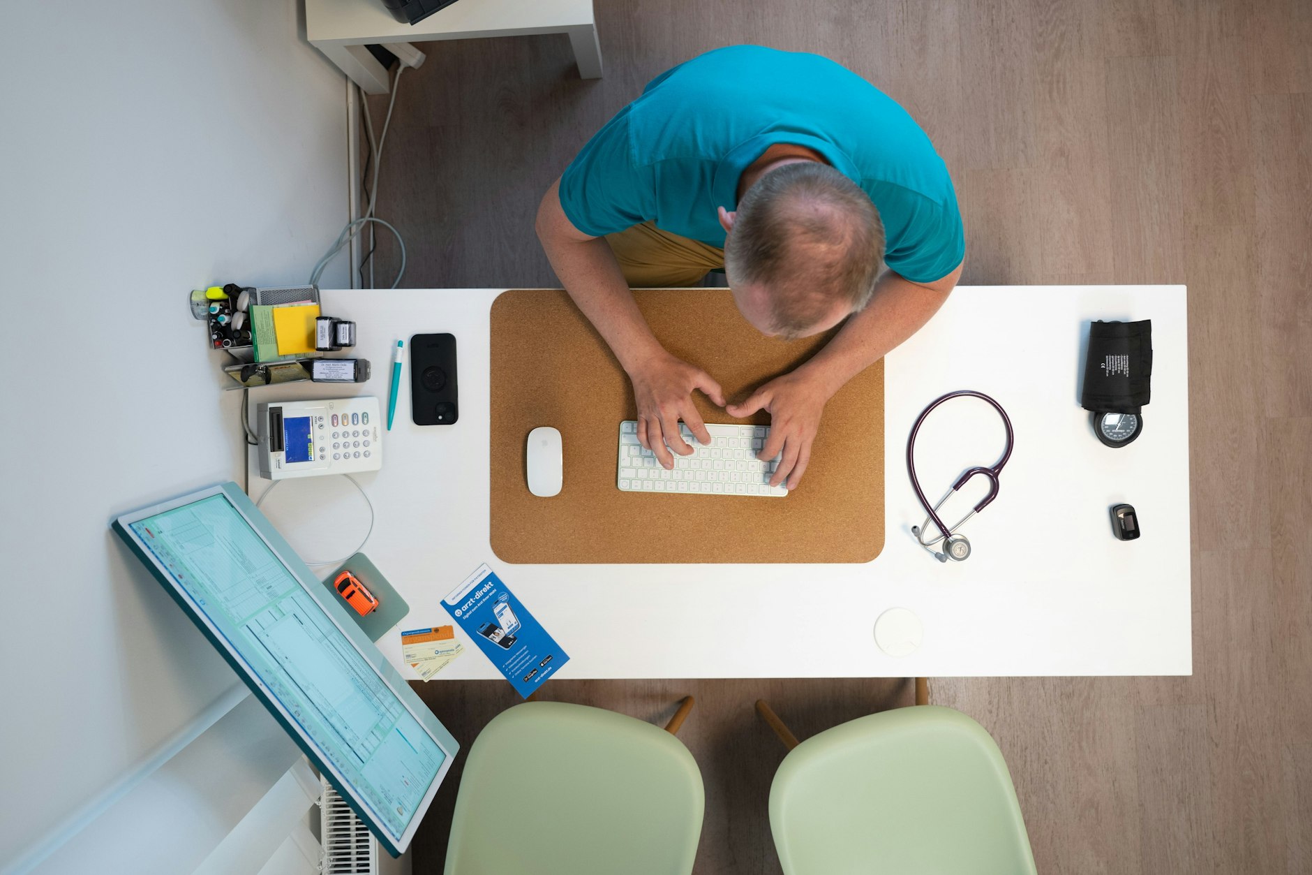 Ein Hausarzt sitzt in einem Sprechzimmer an einem Schreibtisch. Hausärzte sollen künftig Patientenströme steuern.