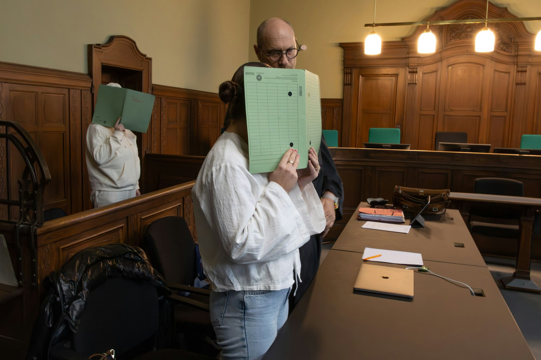 Die Angeklagten verbergen vor Gericht ihre Gesichter.