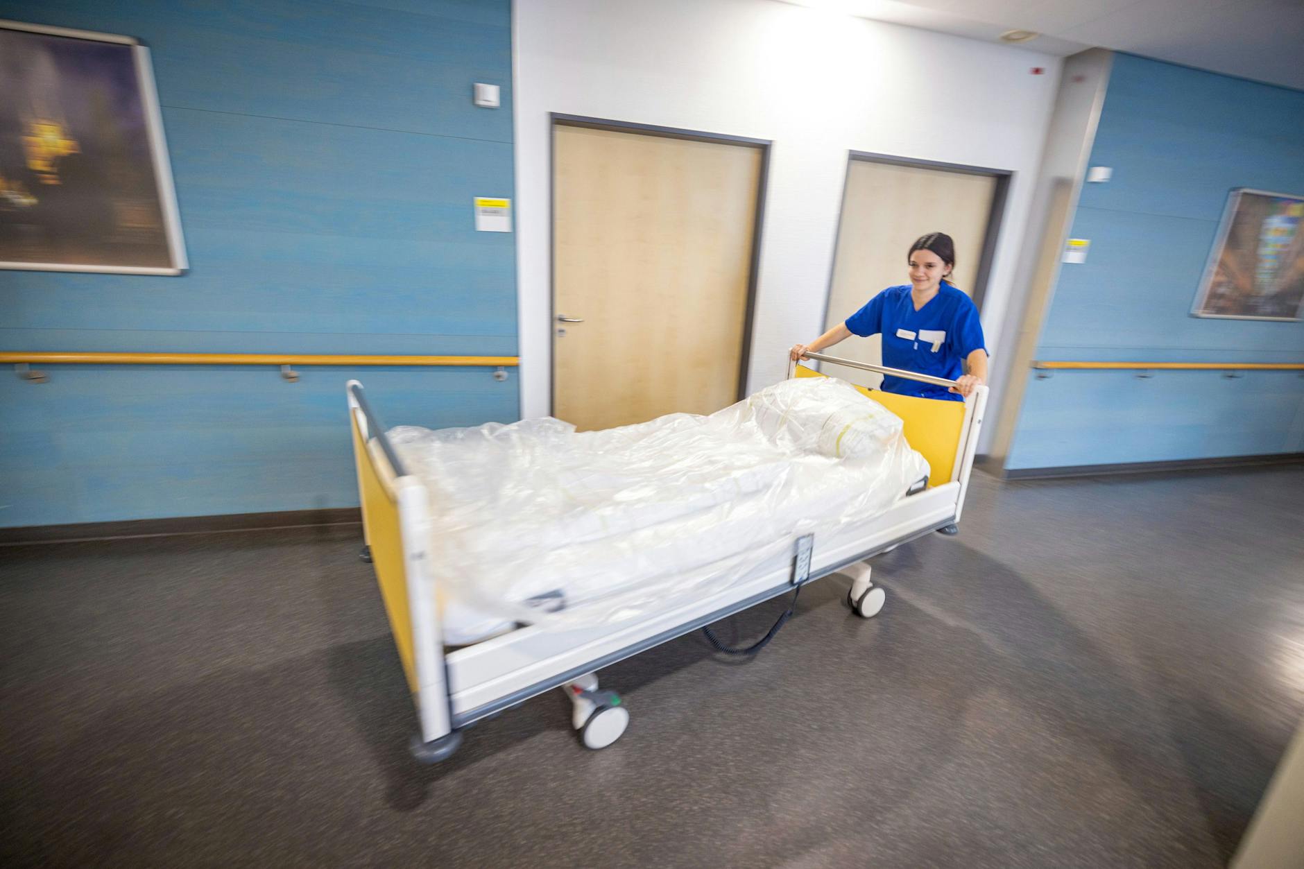 Alltag im Krankenhaus: Eine Pflegekraft schiebt ein Patientenbett einen Flug entlang.