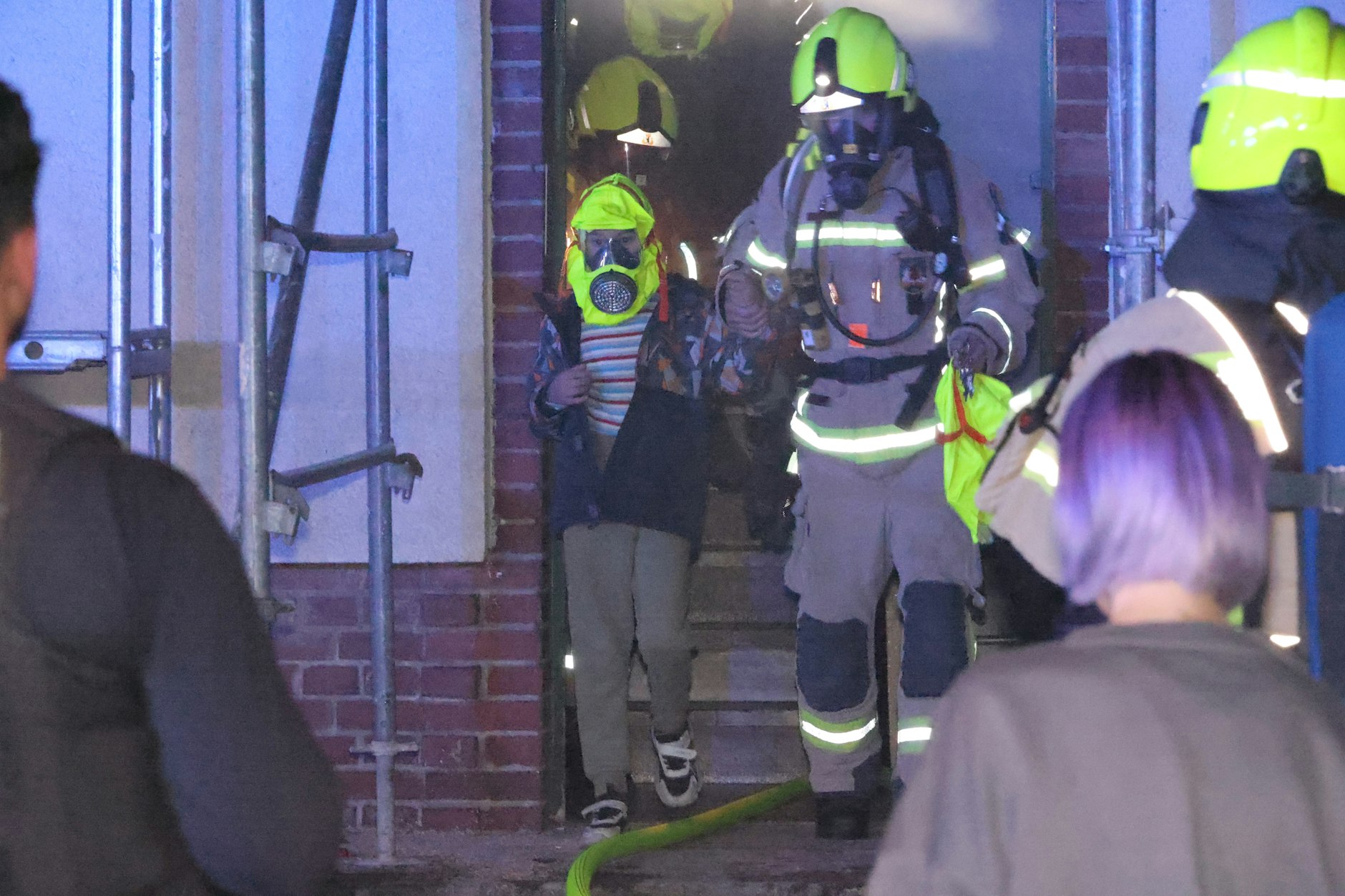 Brand in Mariendorf. Die Feuerwehr bringt Bewohner, hier ein Kind, mit Schutzhaube über den Kopf aus dem Haus.