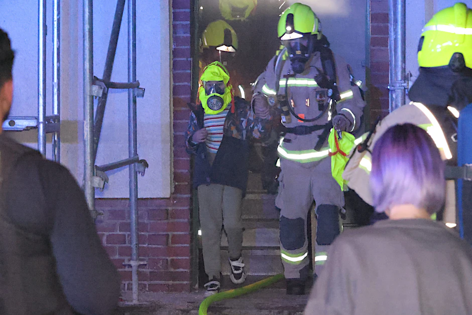Brand in Mariendorf. Die Feuerwehr bringt Bewohner, hier ein Kind, mit Schutzhaube über den Kopf aus dem Haus.