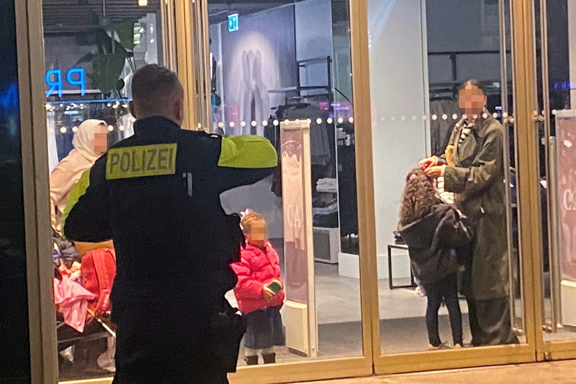 Ladenschluss verpasst: die eingesperrten Mütter mit ihren Kindern hinter der zugesperrten Eingangstür des Mode-Kaufhauses am Alexanderplatz.