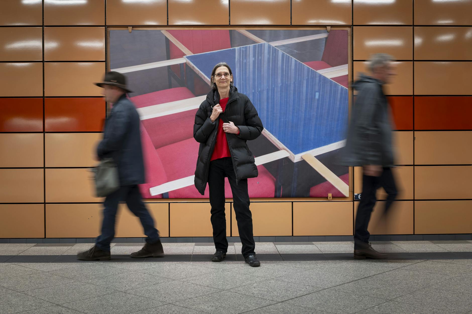 Maria Sewcz im U-Bahnhof Schillingstraße vor einem ihrer neun Wandbilder hinter den Gleisen. Auf dem Motiv Tisch und Sessel des Cafés des derzeit unter Bauplanen versteckten Kinos International