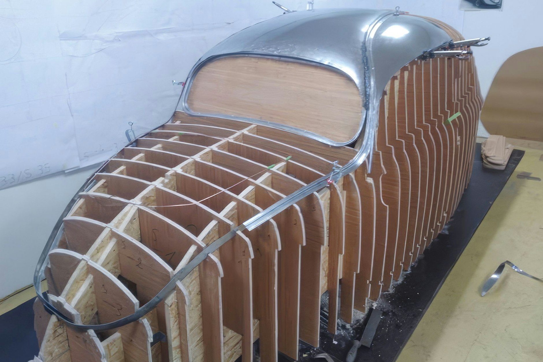 Teile der rekonstruierten Karosserie des Käfer-Prototypen sind auf einem Holzgestell montiert.