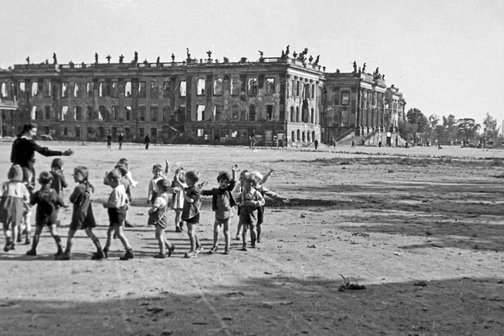 Kindergärtnerin spielt mit ihrer Kindergruppe vor den Ruinen des Potsdamer Stadtschlosses nahe Berlin, Deutschland 1946.