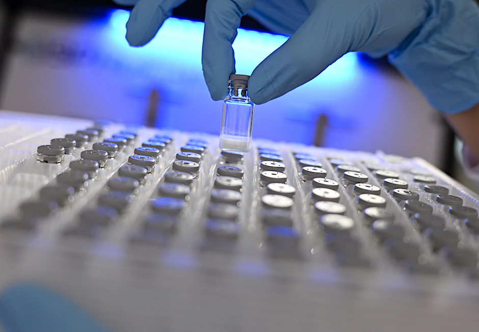 Eine Laborantin entnimmt in einem Labor des Pharma- und Technologiekonzerns Merck eine gefriergetrocknete Probe aus einem Behälter.