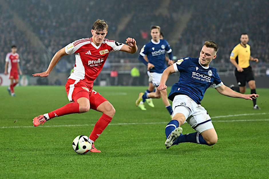Unions Aljoscha Kemlein (l.) versucht im Pokalspiel der 2. Runde 2024/25 den Ball an Bielefelds Leon Schneider vorbeizuspielen.