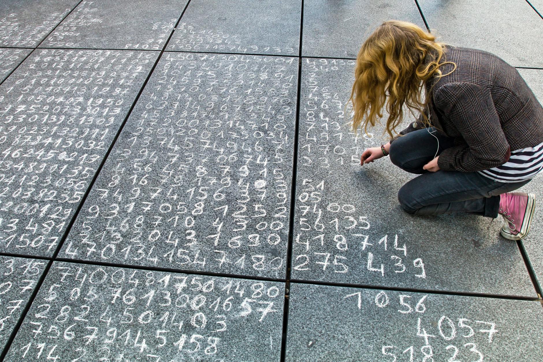 Eine Schülerin hat eine Rechenaufgabe auf ein Straßenpflaster geschrieben.