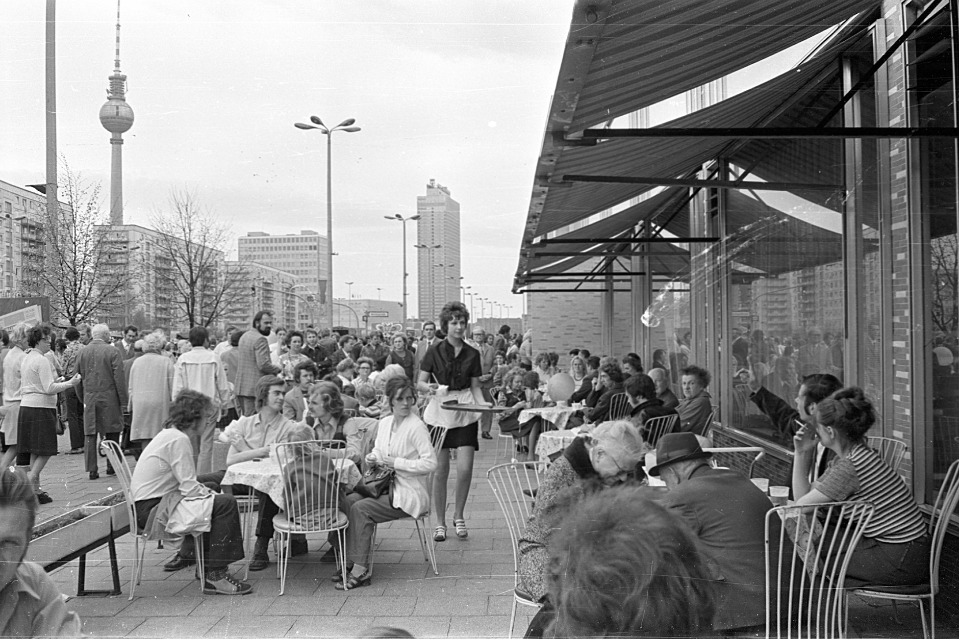 Ost-Berlin,1973: In der Mokka-Milch-Eisbar herrscht Betrieb. Jung und Alt kommen zusammen, die Kellnerin bedient mit weißem Schürzchen.