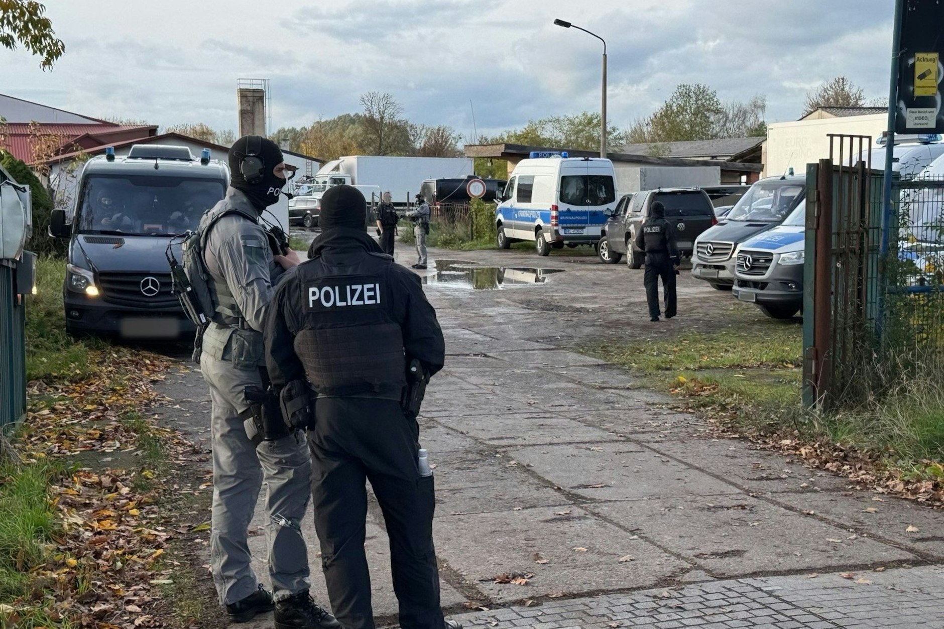 Polizisten stehen am Eingang zum Gelände, auf dem die Razzia stattfand.