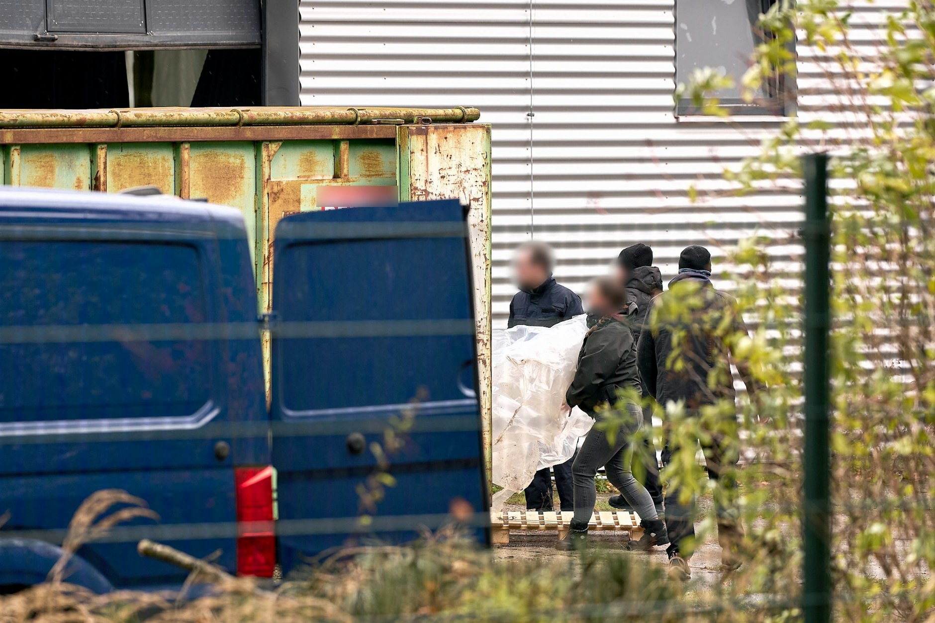 Zollbeamte tragen beschlagnahmtes Material aus der Halle, in der ein riesiges illegales Drogenlabor ausgehoben wurde.
