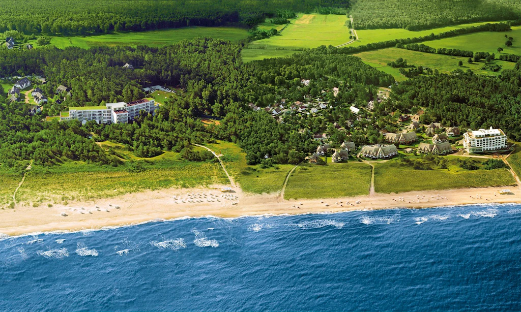 Das Strandhotel Fischland, links umgeben von Küstenwald, ehemals Gästehaus der DDR-Regierung, 800 Meter entfernt das nah am Strand gelegene Strandhotel Dünenmeer. Zu beiden Schwesterhotels gehören Ferienhäuser und -wohnungen.