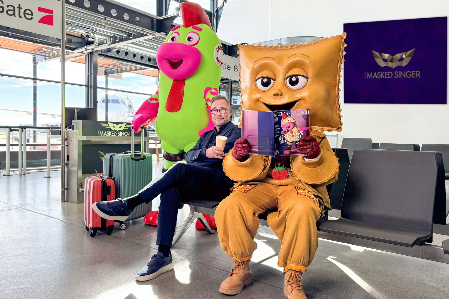 Ein erstes Foto zeigt Matthias Opdenhövel mit den beiden Masken Quietsch und Rave-ioli. Auf dem Bild ist ein kleines Detail versteckt.