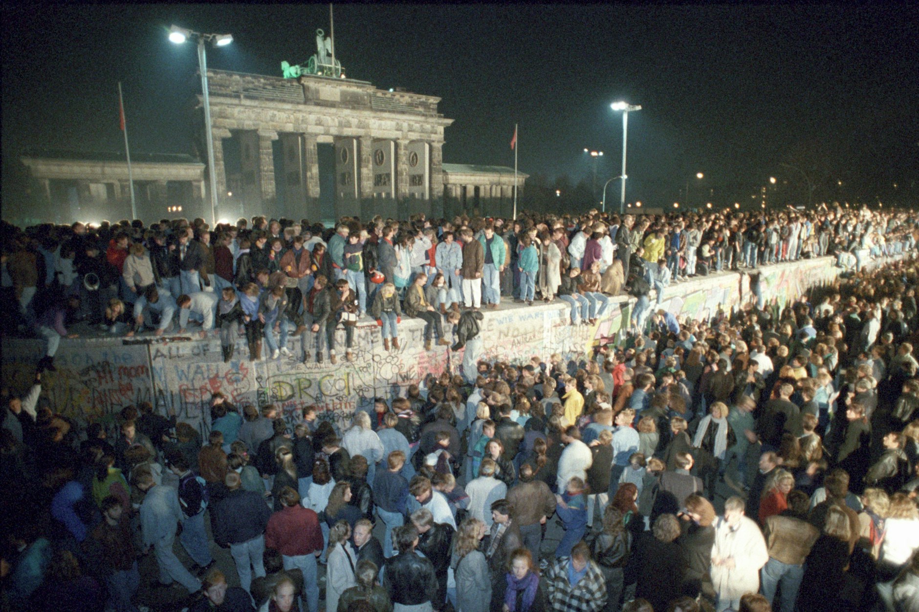 Menschen feiern auf der Berliner Mauer vor dem Brandenburger Tor in der Nacht vom 9. auf den 10. November 1989 den Mauerfall. Wie haben Sie die legendäre Nacht erlebt?