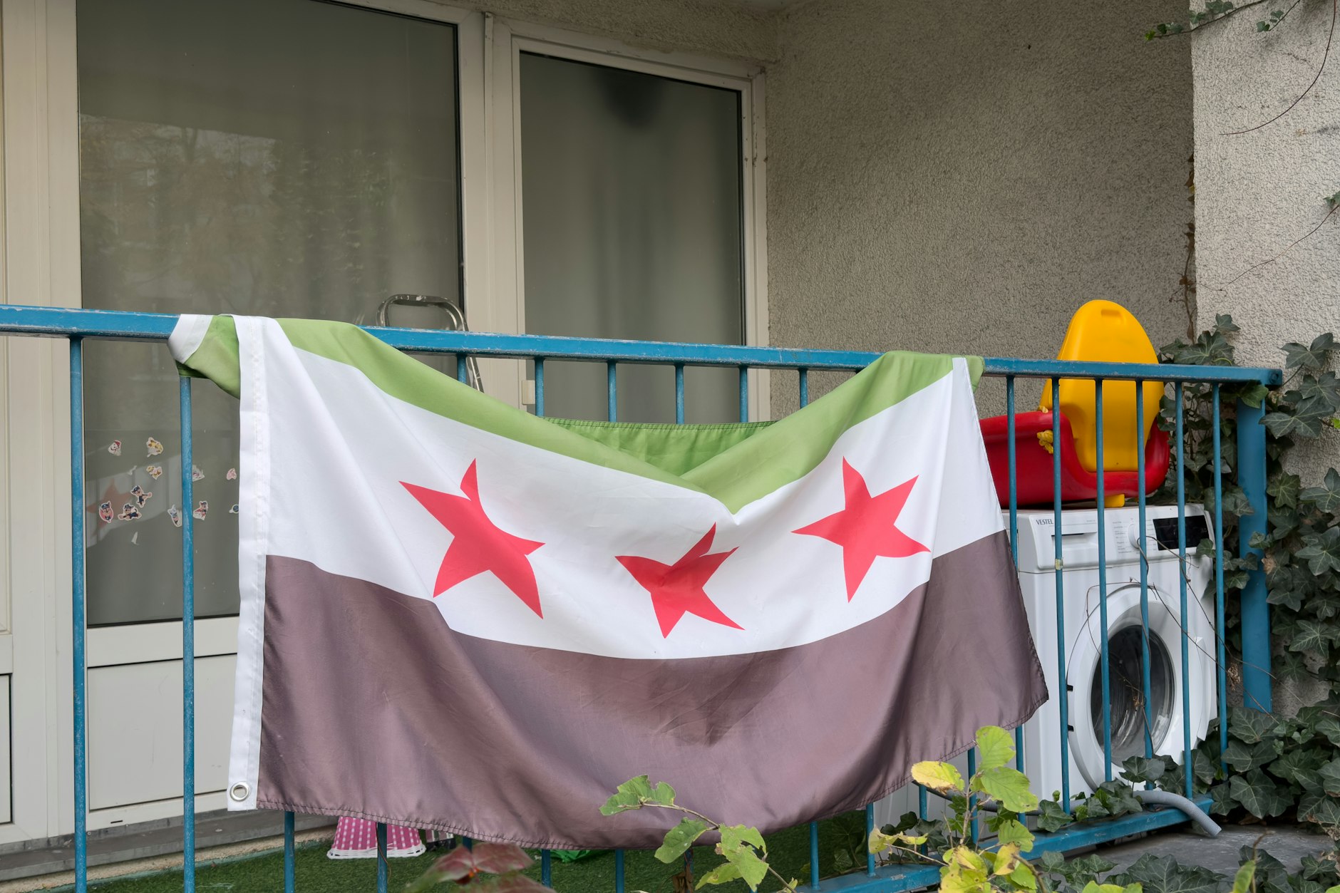 Die syrische Unabhängigkeitsflagge, die auch als Flagge der syrischen Revolution bekannt ist: Sie hängt an einem Balkon in der Lindenstrasse 29 in Berlin-Köpenick – einer der drei durchsuchten Meldeadressen des mutmaßlichen Terroristen.