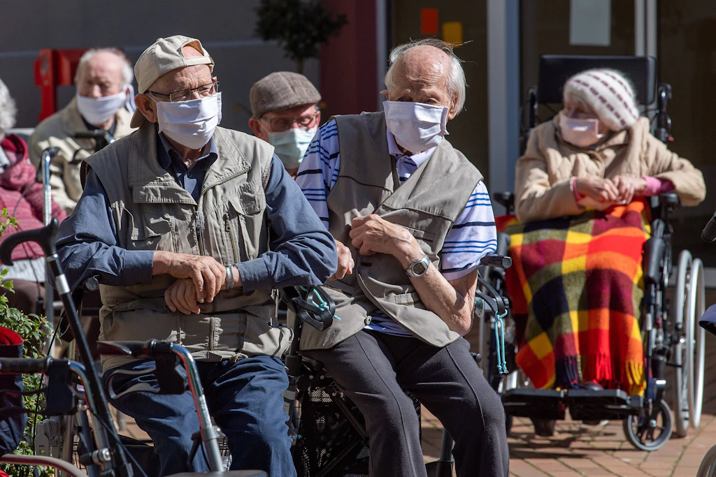Bewohner einer Pflegeeinrichtung in Achim sitzen mit Mundschutz und Masken auf der Terrasse, 2020.