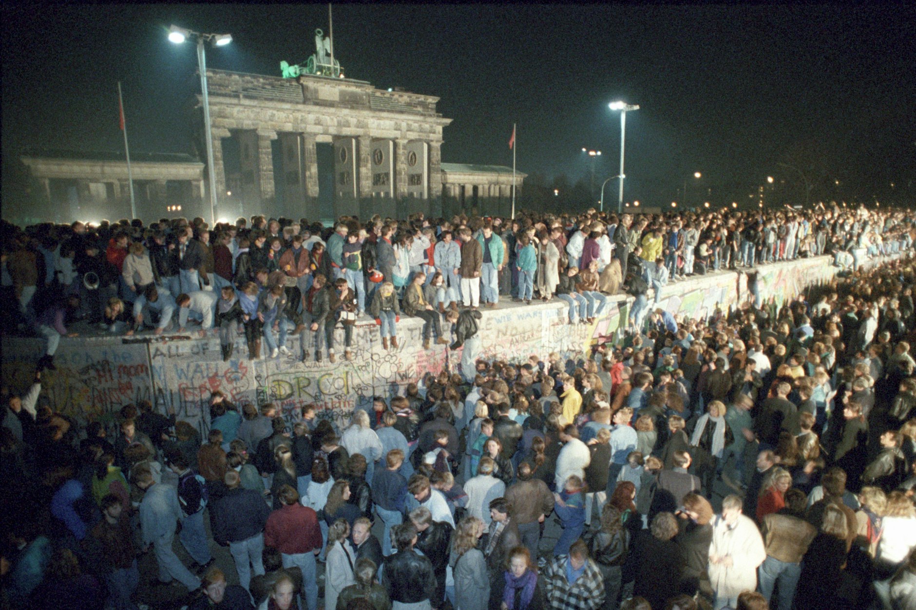 Menschen auf der Berliner Mauer vor dem Brandenburger Tor in der Nacht vom 9. auf den 10. November 1989.