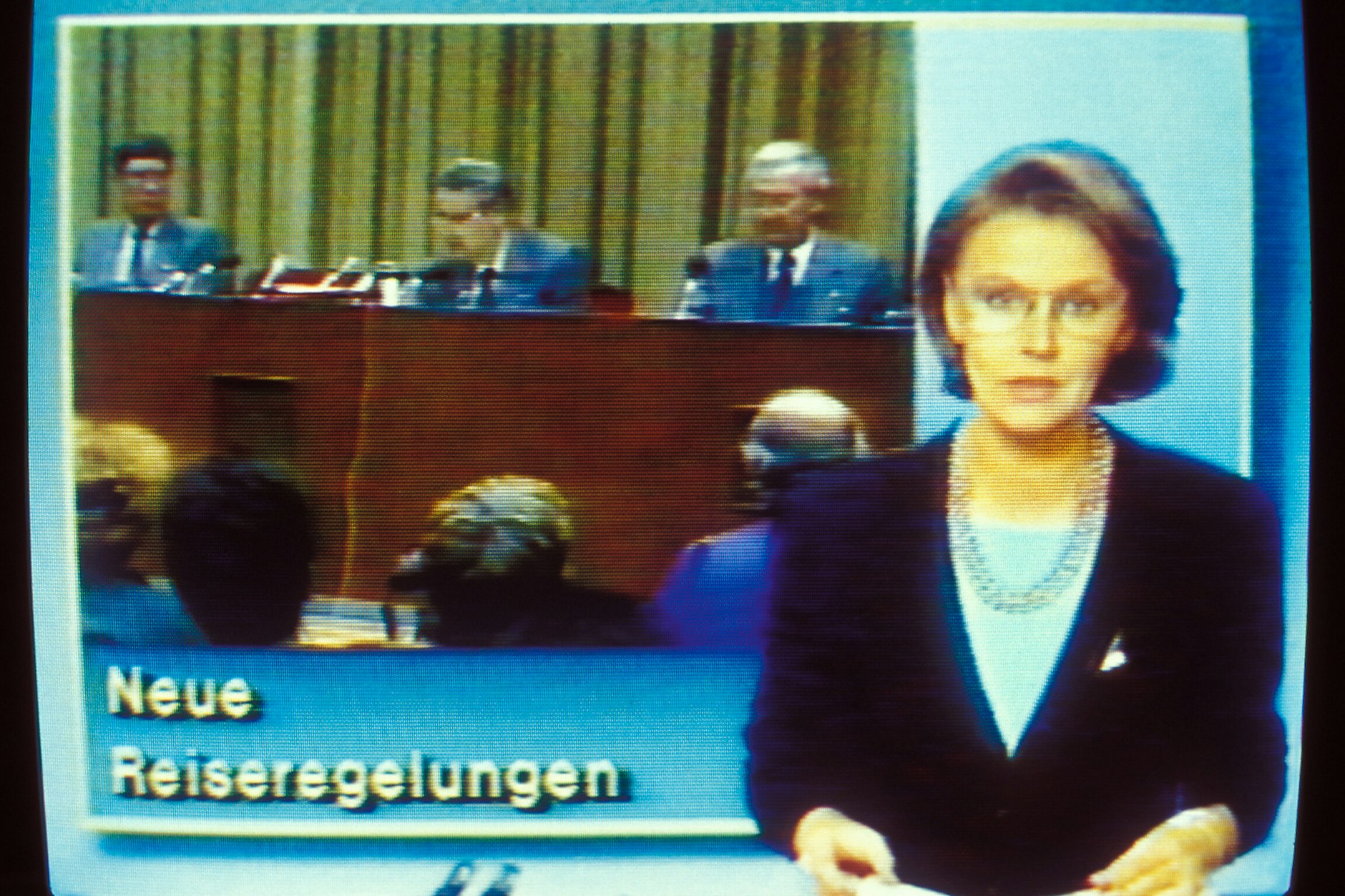 Sprecherin Angelika Unterlauf in der „Aktuellen Kamera“ am Abend des 9. November1989. Im Hintergrund die legendäre Pressekonferenz von Günter Schabowski.