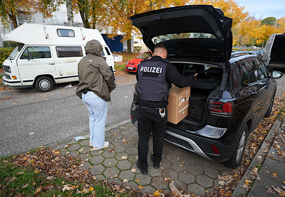 Polizeibeamte transportieren nach der Razzia sichergestelltes Material aus einer Hamburger Wohnung ab.