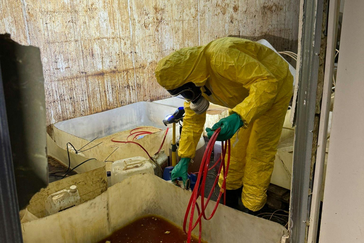 Heftig! Hier sieht man, wie ein Mitarbeiter der Zollfahndung eine Wanne mit Chemikalien im Drogenlabor in Nauen leeren muss.