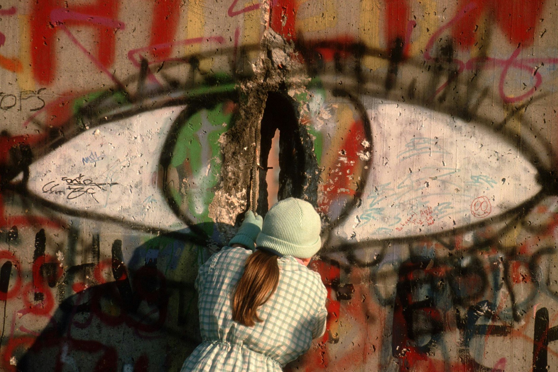 Eine Frau meißelt ein Stück Stein als Andenken aus der Berliner Mauer. Das Foto entstand zum Mauerfall am 9. November 1989.
