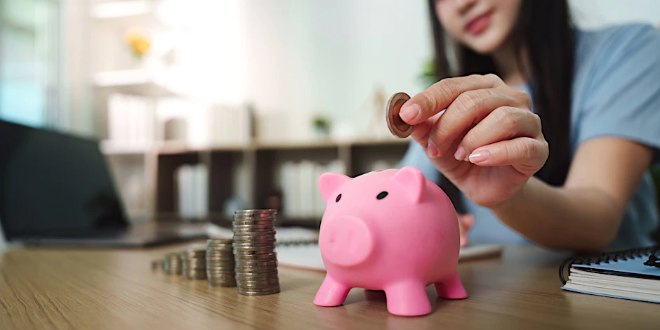 Geld sparen: Junge Frau mit Sparschwein und Münzen