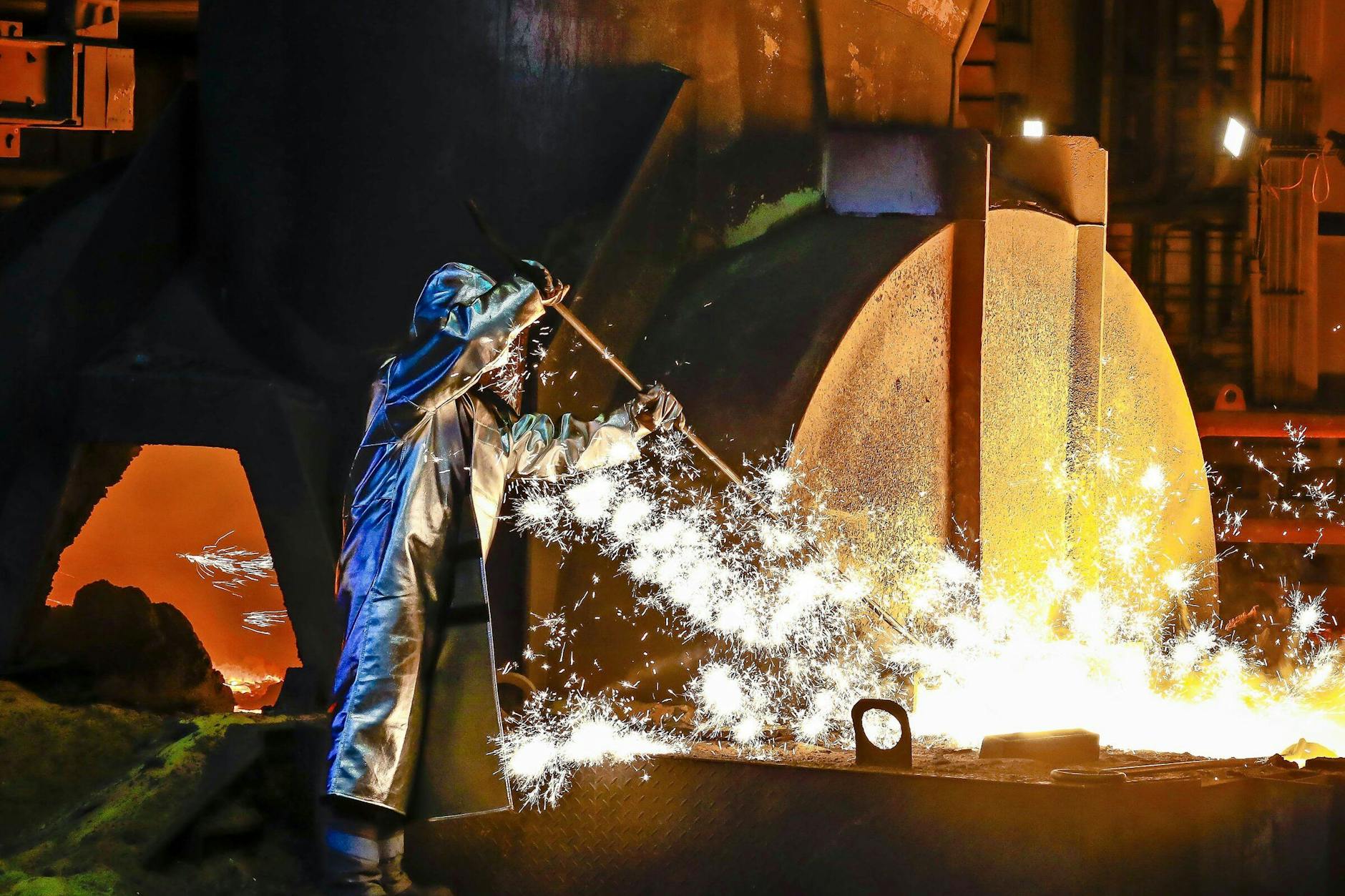 Ein Stahlarbeiter von Thyssenkrupp in Duisburg entnimmt im Schutzanzug eine 1500 Grad heiße Roheisenprobe aus dem Hochofen.