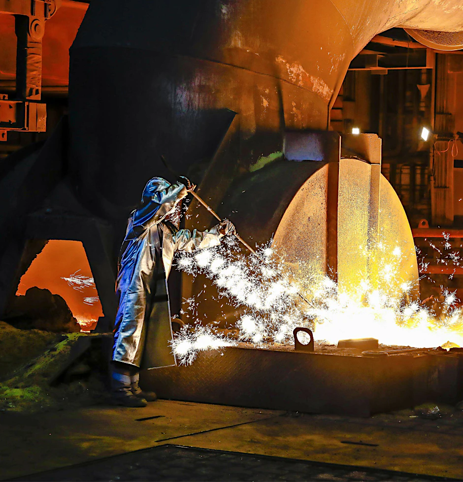 Ein Stahlarbeiter von Thyssenkrupp in Duisburg entnimmt im Schutzanzug eine 1500 Grad heiße Roheisenprobe aus dem Hochofen.
