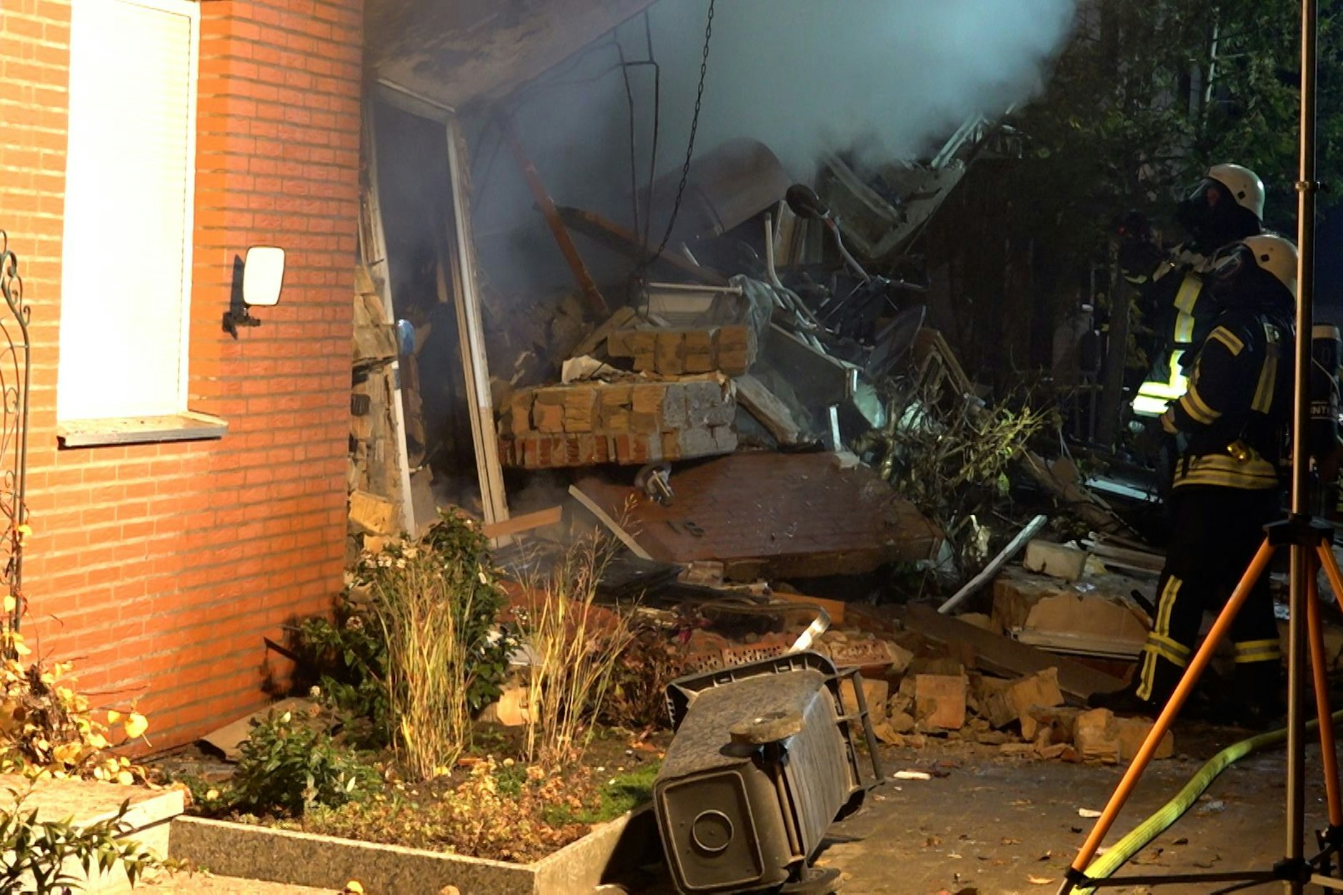 Feuerwehrleute sind im Einsatz am zerstörten Reihenhaus.