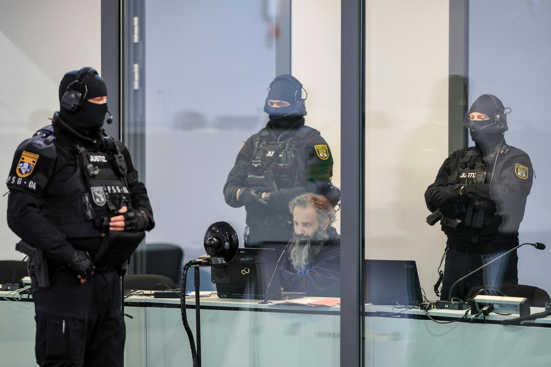 eburg: Der Angeklagte Taleb A. sitzt mit Handfesseln in dem kugelsicheren Glaskasten Gerichtssaal im temporären Gerichtsgebäude des Landgerichtes Magdeburg.