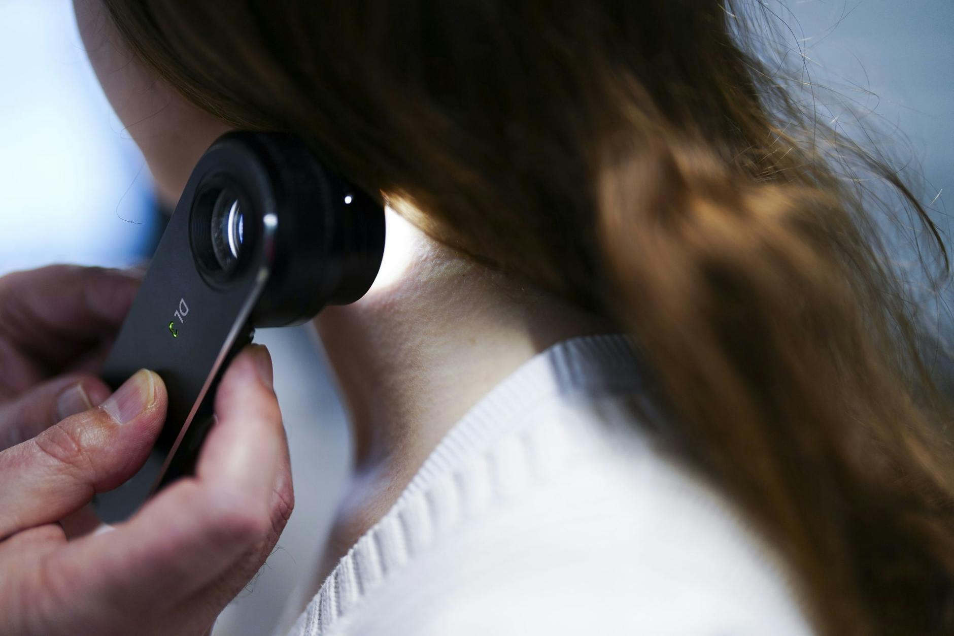 Ein Hautarzt sucht eine Patientin nach bösartigen Hautveränderungen ab. Einige Krankenkassen tragen die Screening-Kosten.