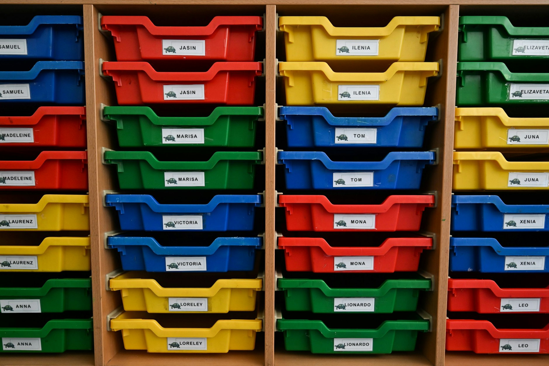 In einem Klassenraum sind bunte Plastikschubkästen mit den Namen der neuen Erstklässler versehen.