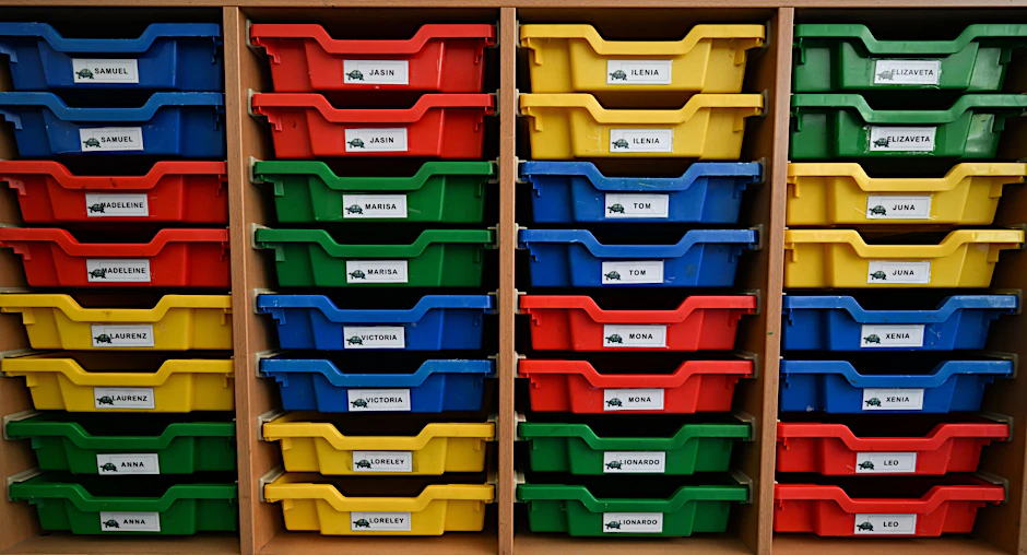 In einem Klassenraum sind bunte Plastikschubkästen mit den Namen der neuen Erstklässler versehen.