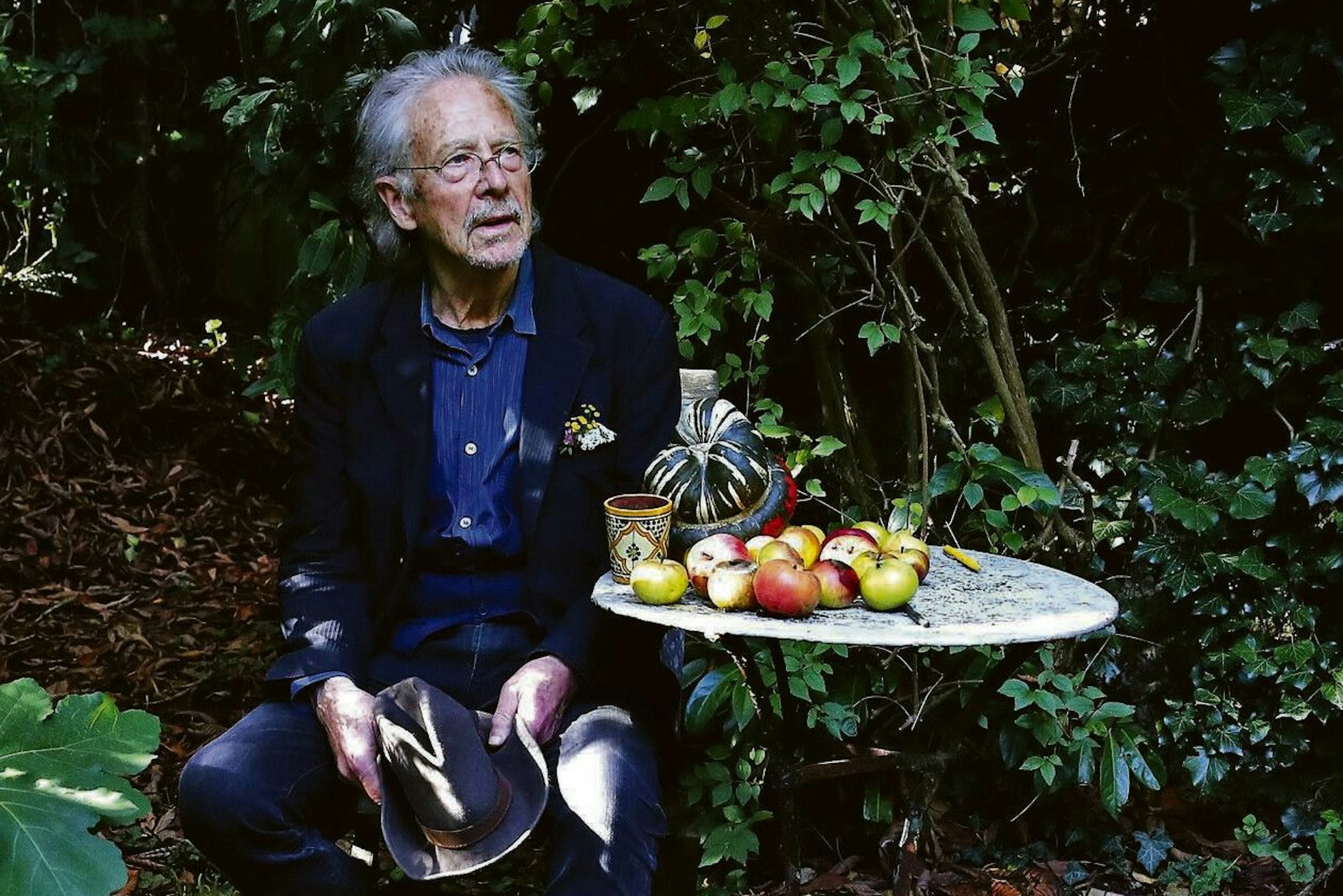 Peter Handke sitzt in seinem Garten bei seinem Haus in Chaville.