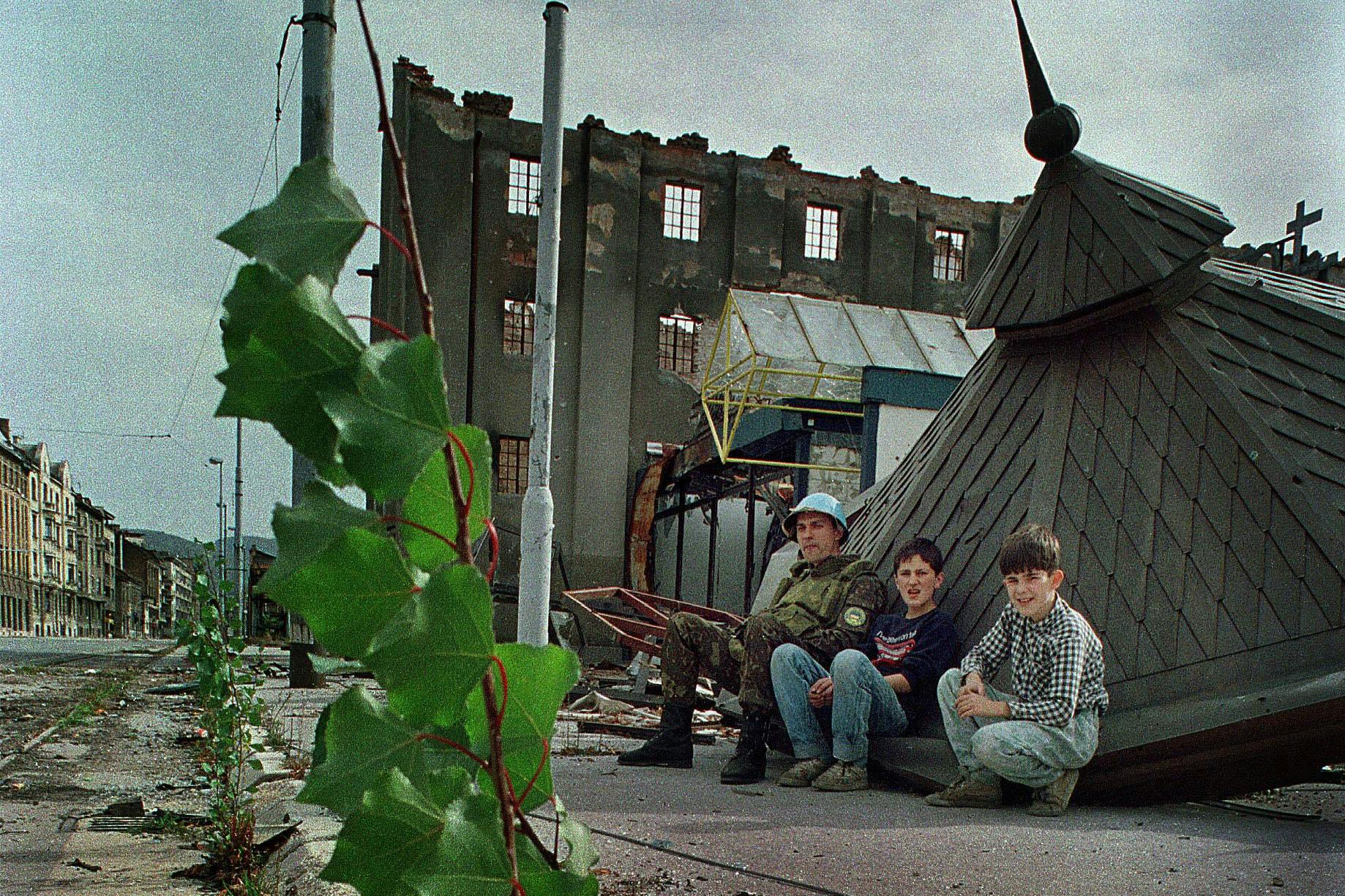 Jugendliche und ein ukrainischer Blauhelmsoldat gehen in der berüchtigten Sniper-Allee in Sarajevo in Deckung