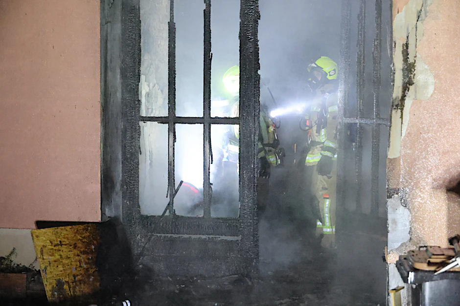 Geschützt mit Atemmasken erkunden Feuerwehrleute das verqualmte Haus.