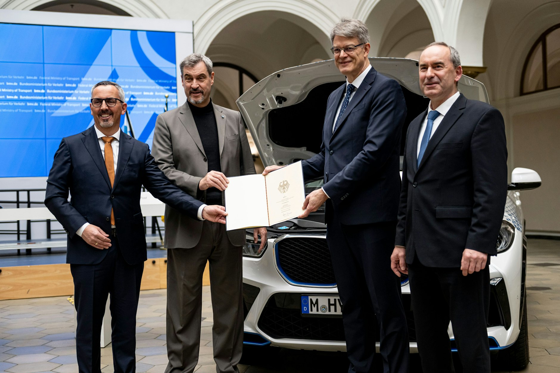 Bayerns Ministerpräsident Markus Söder (2.v.l., CSU) und Bundesverkehrsminister Patrick Schnieder (2.v.r., CDU) bei der Fördermittelübergabe für das Wasserstoffprojekt von BMW.