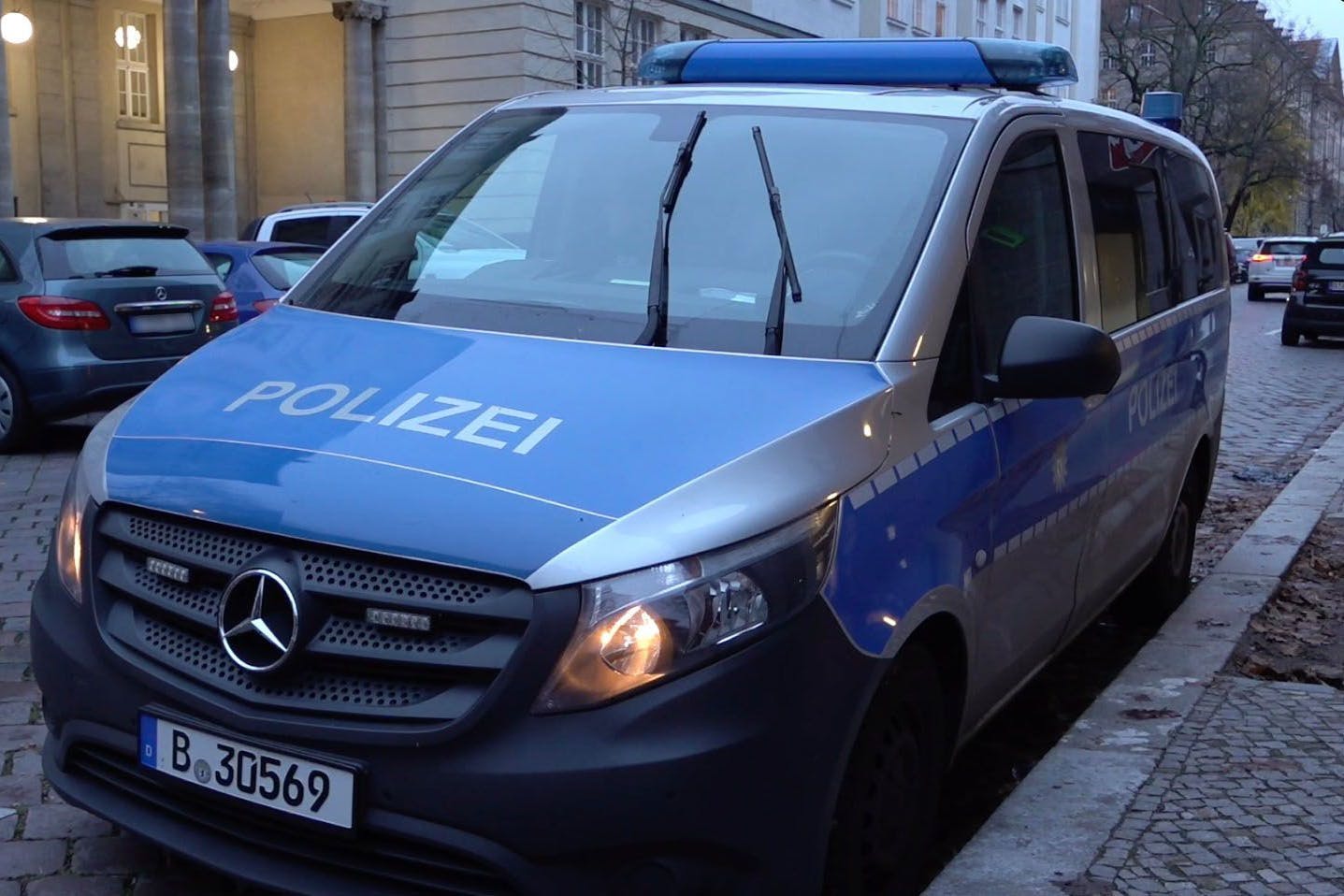 Ein Polizeiauto steht vor einer Berliner Schule.