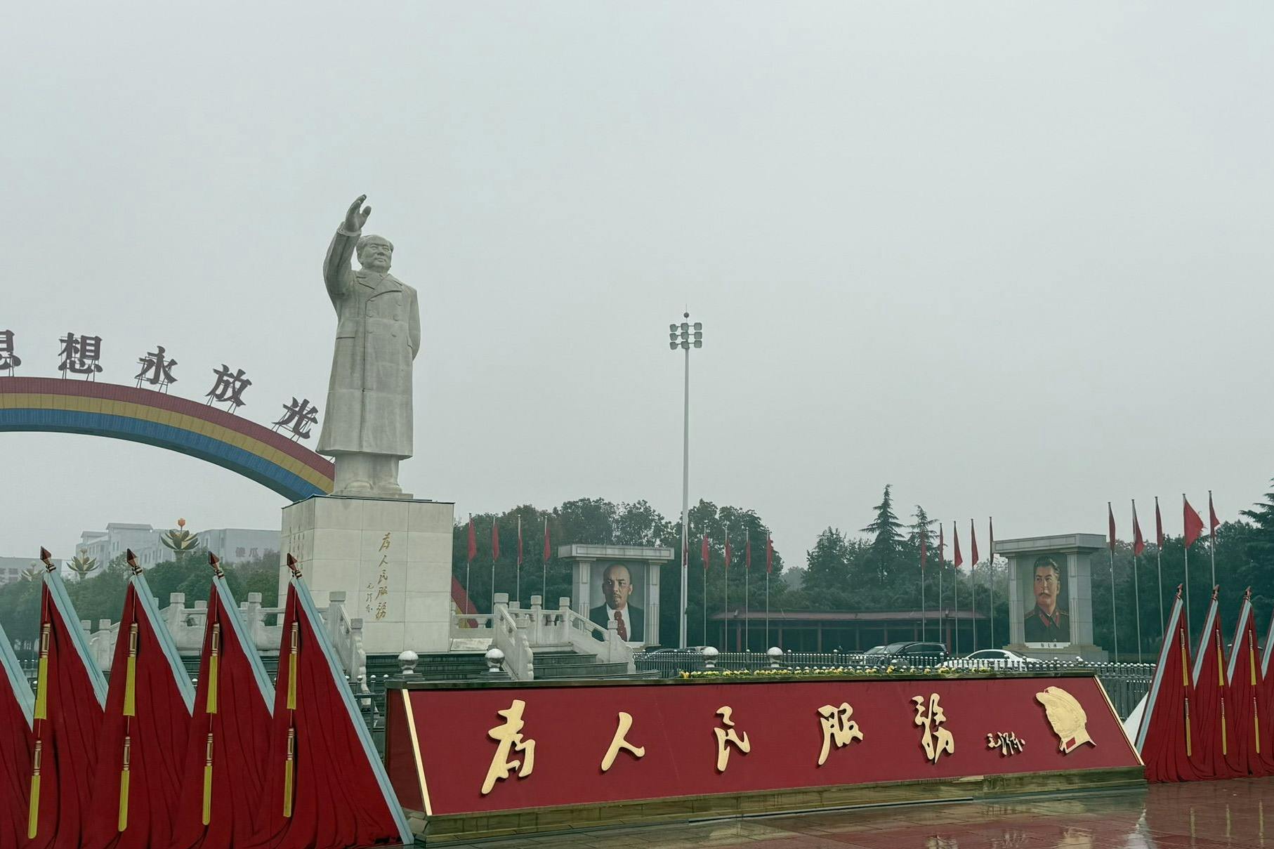 Besucher werden vom (Über-)Großen Vorsitzenden begrüßt, flankiert von Porträts von Marx, Engels, Stalin und Lenin.