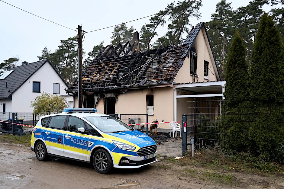 Die Polizei Brandenburg vor dem ausgebrannten Reihenhaus in Michendorf. Bei dem Feuer gab es eine Tote. Die Ermittler prüfen derzeit, ob ein Zusammenhang zu einem Autounfall ganz in der Nähe besteht, bei dem ein Mann starb.