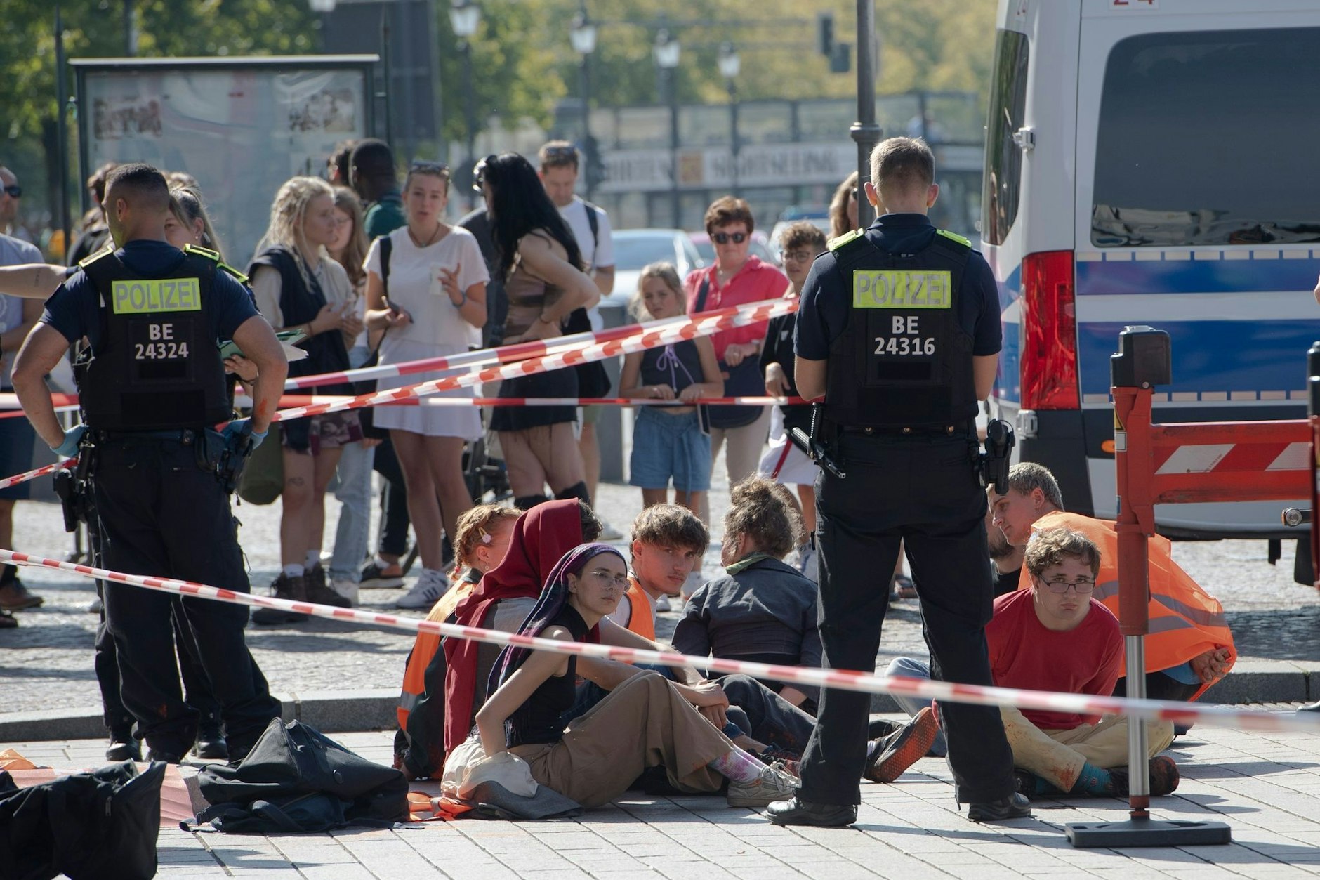 Polizeibeamte stehen um eine Gruppe von Klima-Aktivisten der „Letzten Generation“, die sie nach der Farbattacke auf das Brandenburger Tor festgenommen hatten.