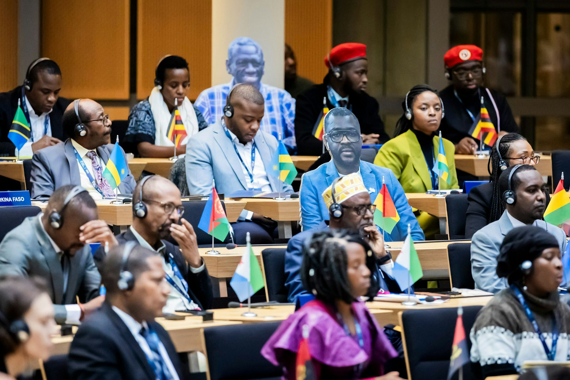 Teilnehmer sitzen bei der Eröffnungssitzung des World Liberty Congress im Berliner Abgeordnetenhaus zum Start der Berlin Freedom Week neben Aufstellern aus Pappe, die Nicht-Anwesende Delegierte zeigen.