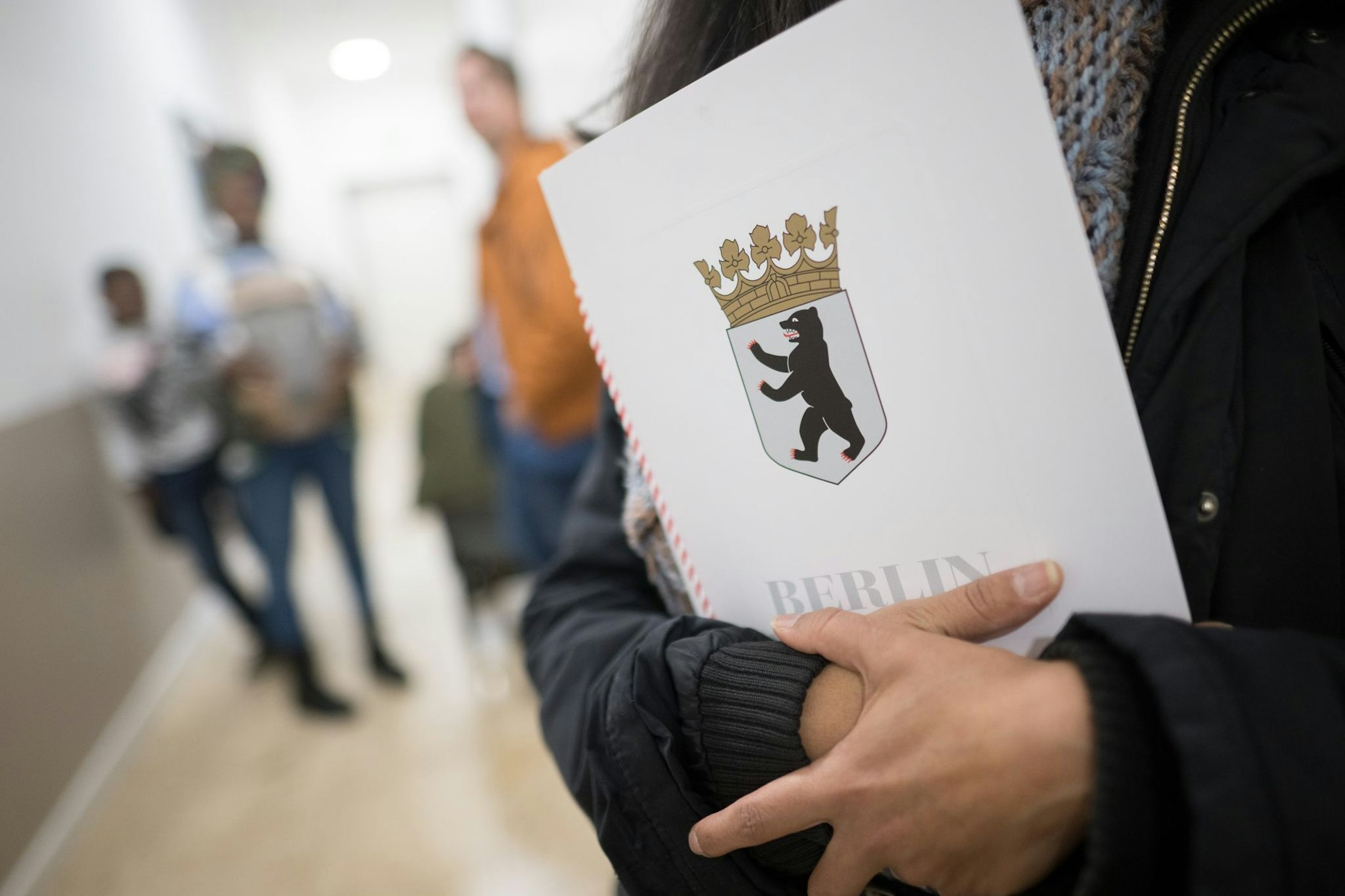 Eine Frau hält im Landesamt für Einwanderung (LEA) ihre Einbürgerungsurkunde in der Hand.