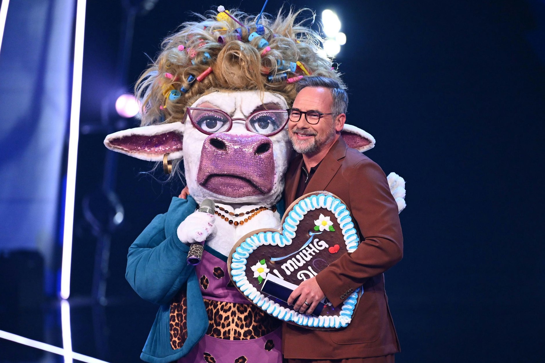Matthias Opdenhövel mit der Kuh Muuhnika auf der Bühne von Masked Singer. Fans glauben, dass unter der Maske Komikerin Meltem Kaptan steckt.