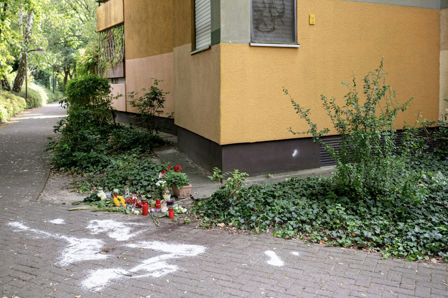 Kerzen und Blumen stehen und liegen in Berlin-Zehlendorf. Eine 36-jährige Mutter von vier Kindern war 2024&nbsp; mutmaßlich von ihrem früheren Ehemann auf einer Straße getötet worden.