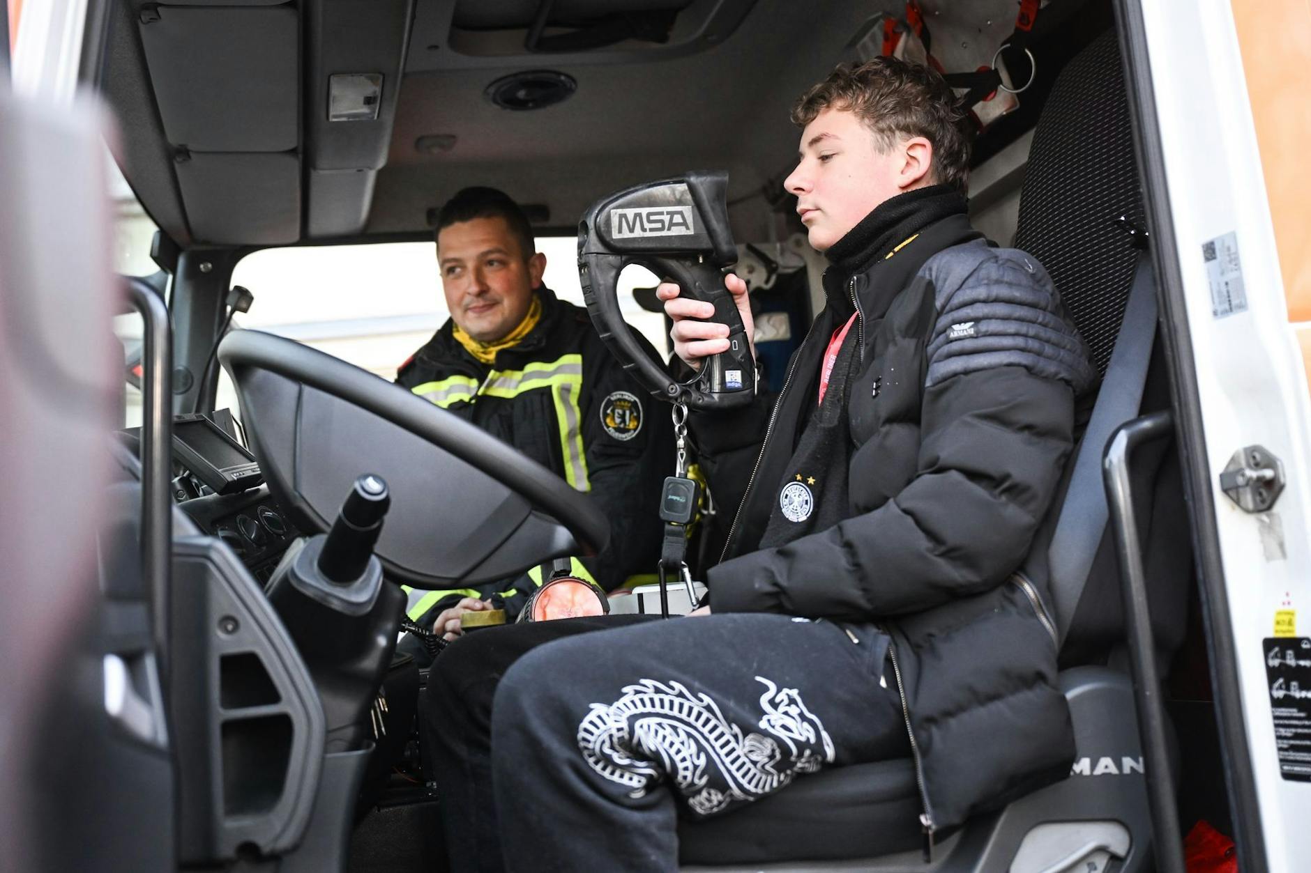 Feuerwehrmann Max Füting erklärt dem 14-jährigen Colin, wie eine Wärmebildkamera funktioniert.